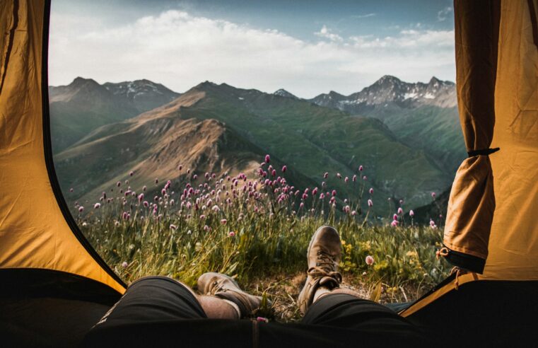 person lying inside tent and overlooking mountain